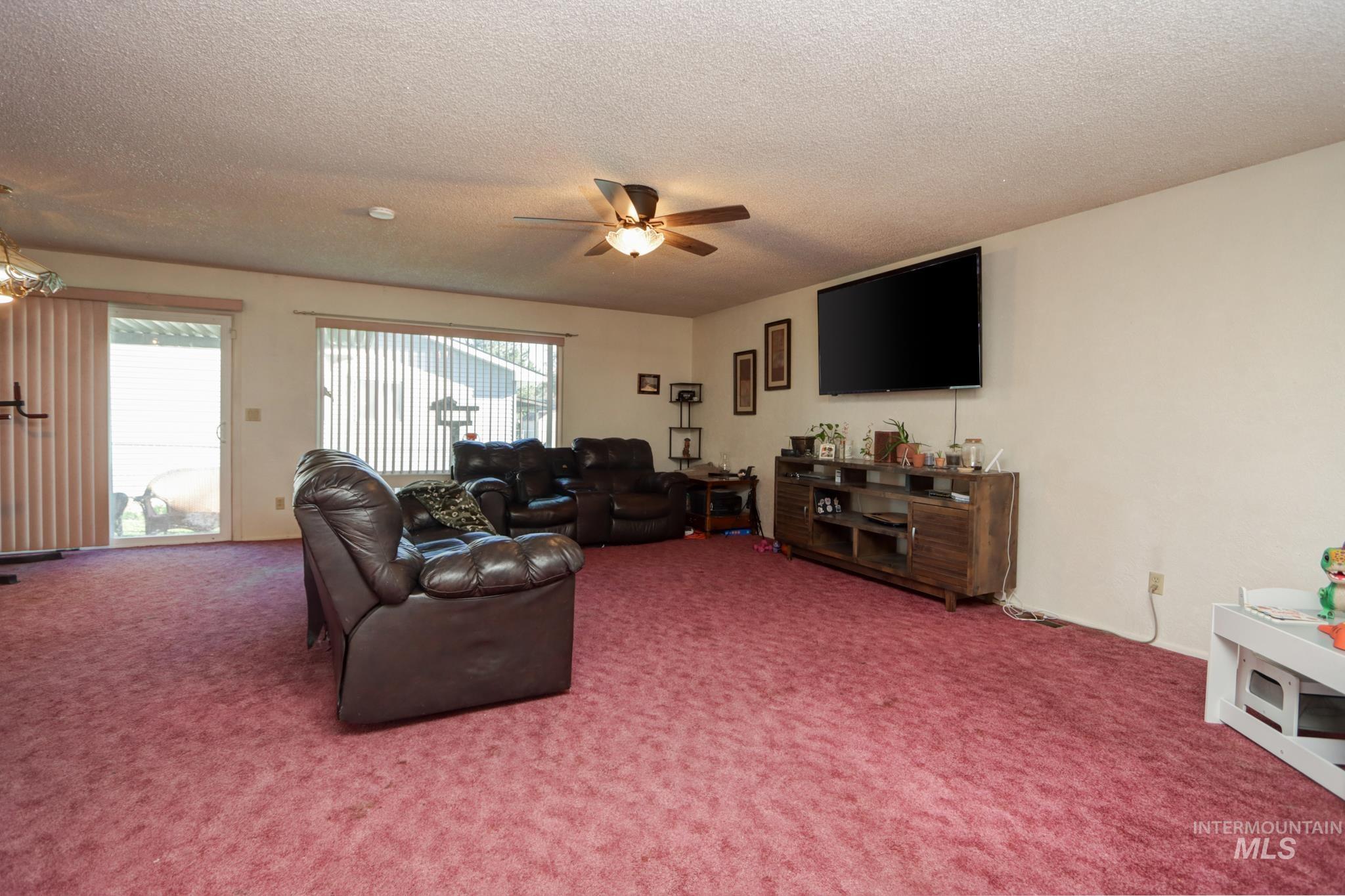 1302 Southwest 12th Street Ontario, OR 97914 - Photo 4 of 35 Living room featuring carpet floors, ceiling fan, and a textured ceiling