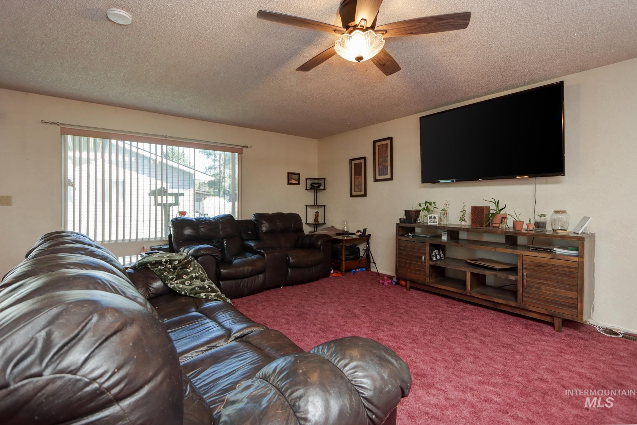 1302 Southwest 12th Street Ontario, OR 97914 - Photo 5 of 35 Living room featuring carpet flooring, a textured ceiling, and a ceiling fan