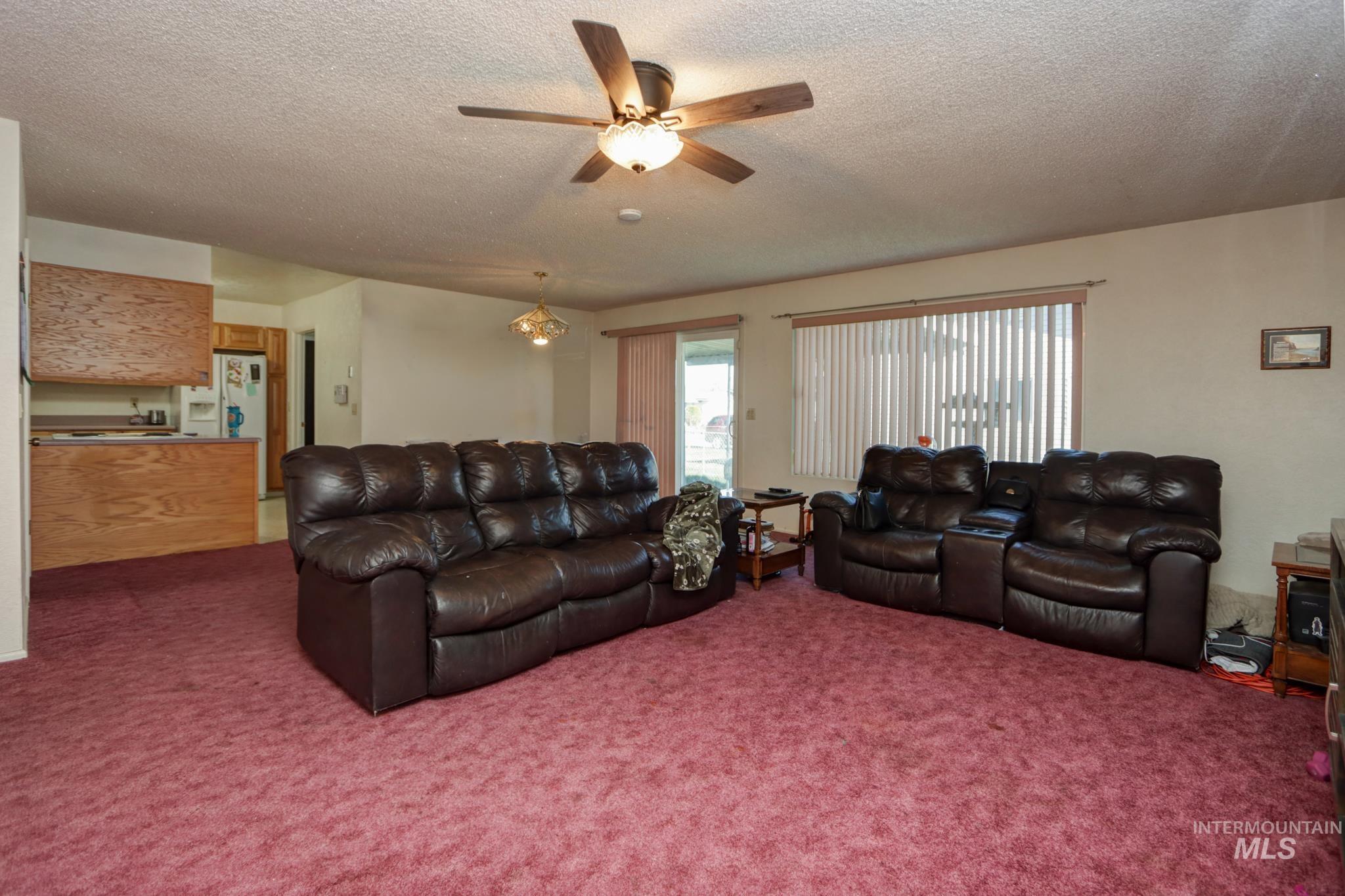 1302 Southwest 12th Street Ontario, OR 97914 - Photo 7 of 35 Living room featuring a textured ceiling, a ceiling fan, and carpet floors
