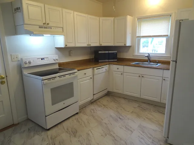 a kitchen with granite countertop white cabinets and white appliances
