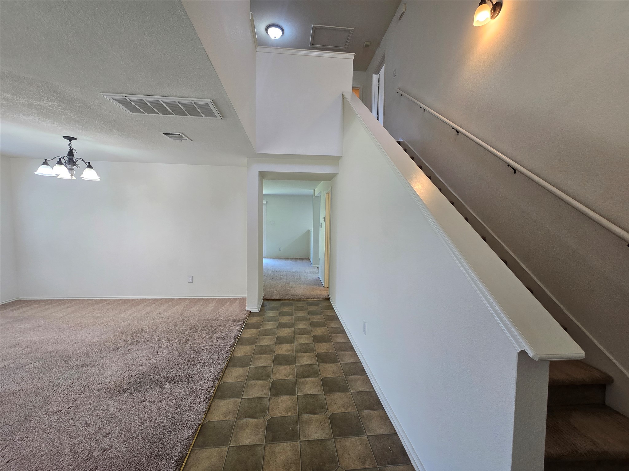 2021 Rim Rock Drive Leander, TX 78641 - Photo 2 of 14 A split-level interior showcases a transition from tile to carpeted flooring, leading to a staircase.