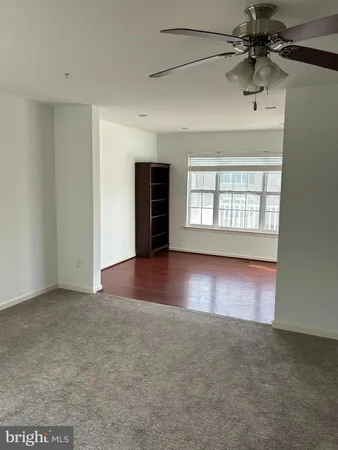 an empty room with windows and chandelier fan
