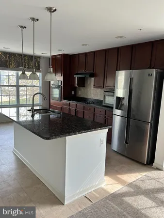a kitchen with stainless steel appliances a refrigerator a sink a stove and a wooden floors