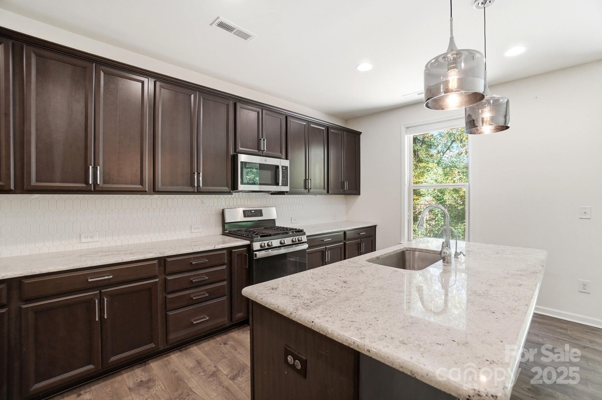 4325 Hunton Dale Road Northwest Concord, NC 28027 - Photo 12 of 42 a kitchen with a stove a sink a microwave a dining table and chairs
