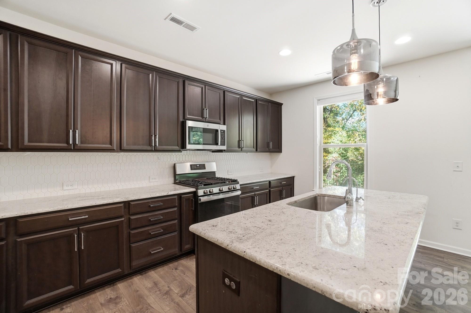 4325 Hunton Dale Road Northwest Concord, NC 28027 - Photo 13 of 42 a kitchen with a stove a sink a microwave a dining table and chairs