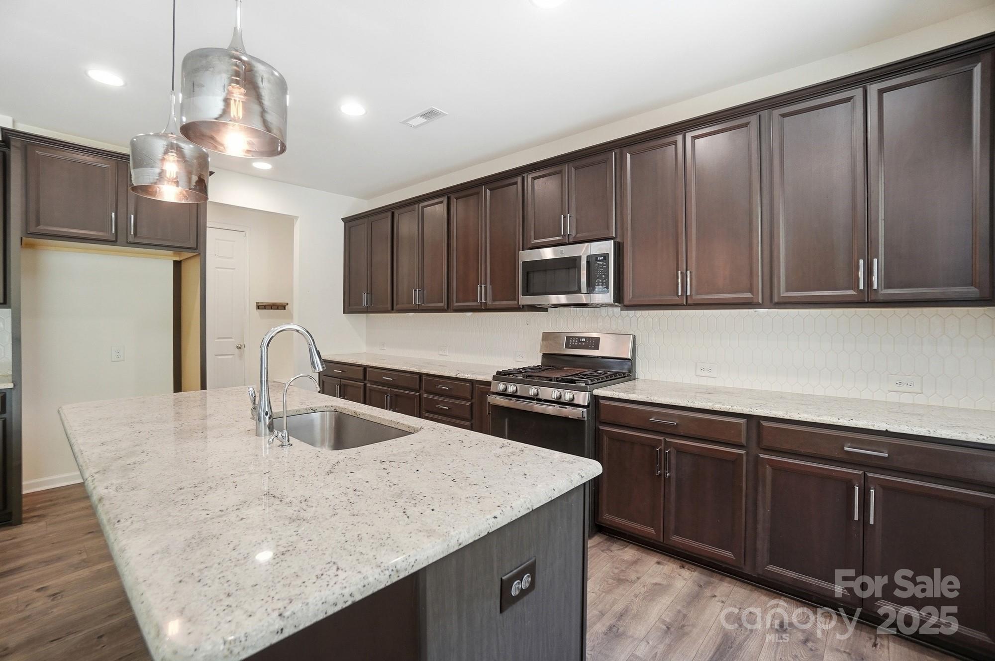 4325 Hunton Dale Road Northwest Concord, NC 28027 - Photo 13 of 42 a kitchen with a sink a stove a microwave and wooden cabinets