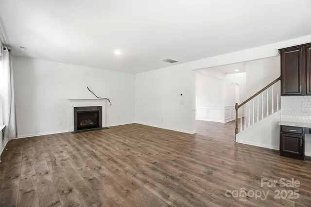 a view of empty room with wooden floor and fireplace