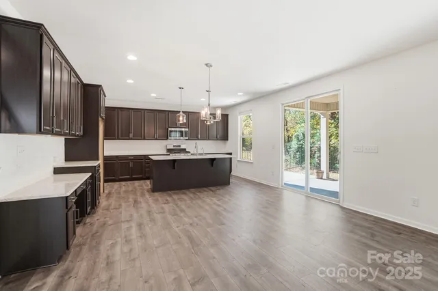 a large kitchen with kitchen island a sink wooden floor and stainless steel appliances