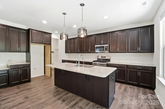 a kitchen with kitchen island granite countertop stainless steel appliances and wooden cabinets