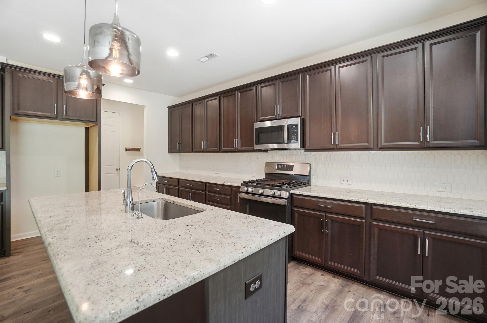 4325 Hunton Dale Road Northwest Concord, NC 28027 - Photo 10 of 42 a kitchen with stainless steel appliances granite countertop a sink dishwasher a stove top oven a refrigerator with island and chairs