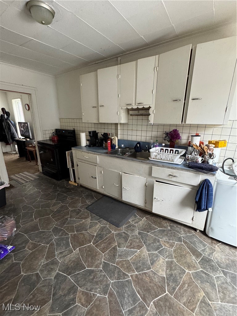 342 West Prospect Road Ashtabula, OH 44004 - Photo 7 of 26 Kitchen with tasteful backsplash, range, white cabinets, and washer / clothes dryer