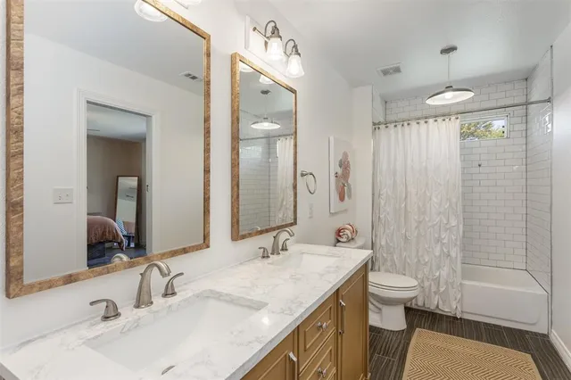 a bathroom with a granite countertop sink a toilet a mirror a shower and a bathtub