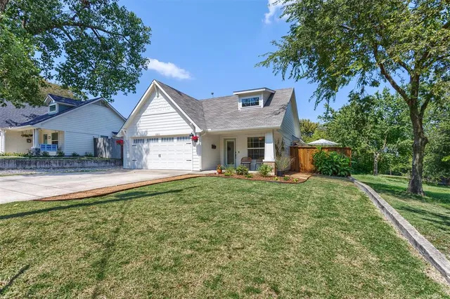 a view of a house with a yard and large tree