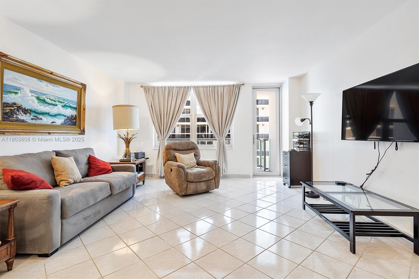 9511 Collins Avenue, Unit 1002 Surfside, FL 33154 - Photo 6 of 27 a living room with furniture and a flat screen tv