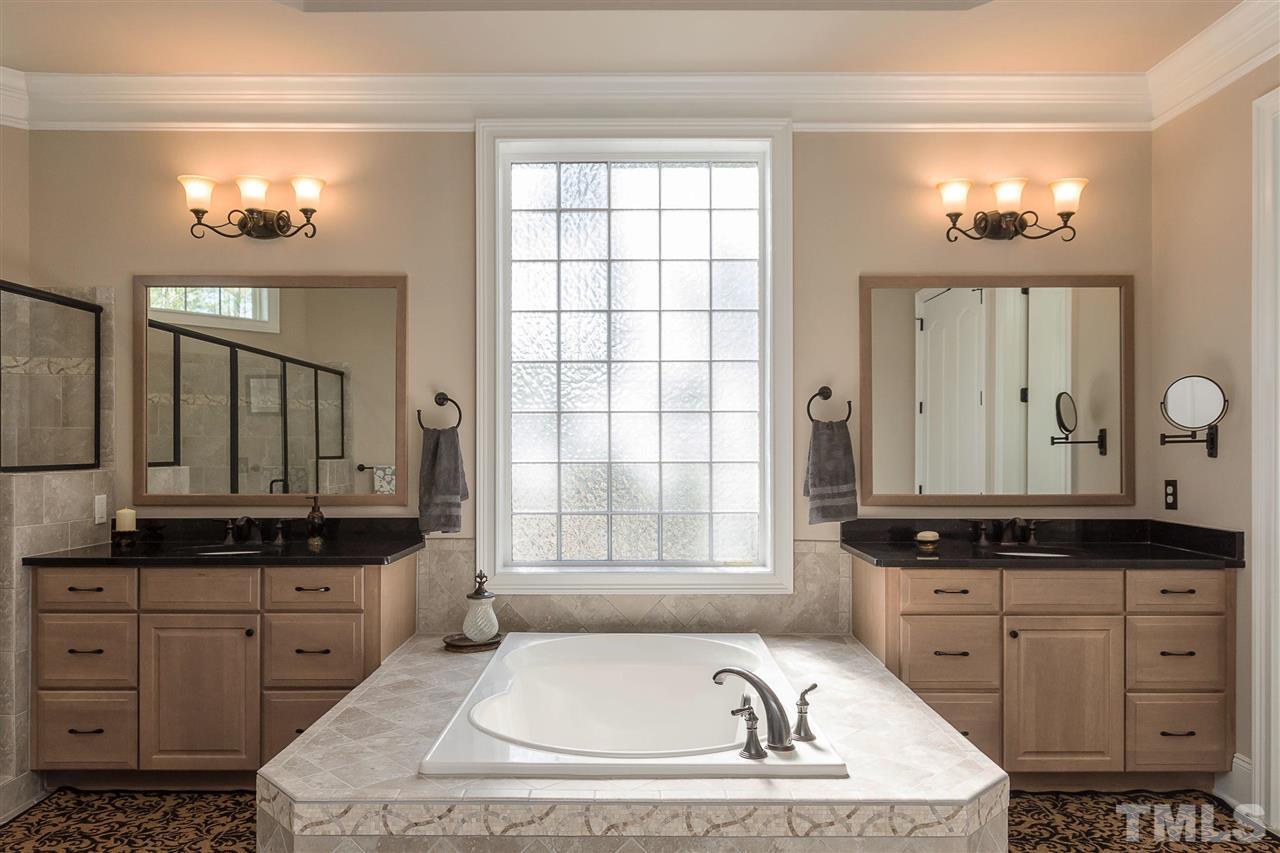 3929 Colinwood Lane Raleigh, NC 27606 - Photo 9 of 24 a bathroom with a granite countertop sink a mirror a window and a bathtub