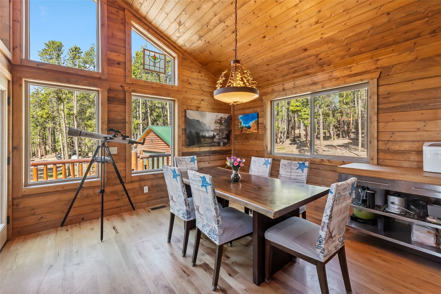 a dining room with wooden floor a chandelier a wooden table and chairs