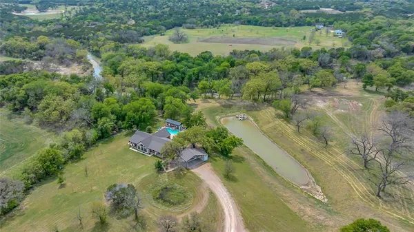 an aerial view of a residential houses with outdoor space and trees