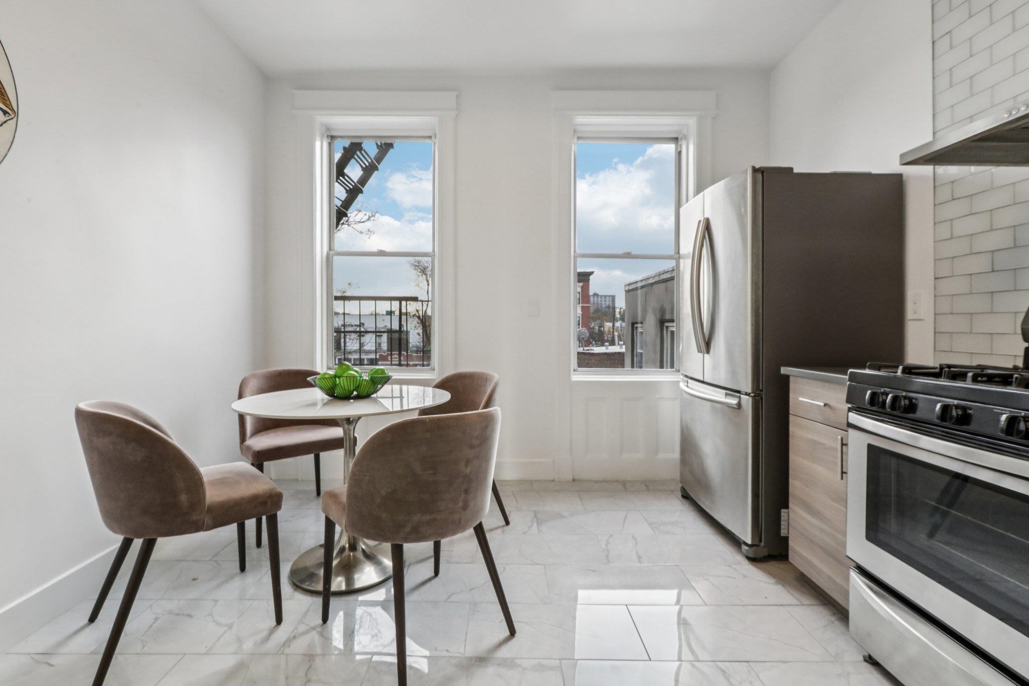 97 Clifton Terrace, Unit 6 Weehawken, NJ 07086 - Photo 11 of 36 a kitchen with stainless steel appliances a refrigerator a stove a dining table and chairs