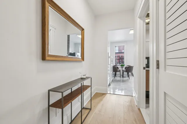 a view of a hallway with wooden floor stairs and a dining room