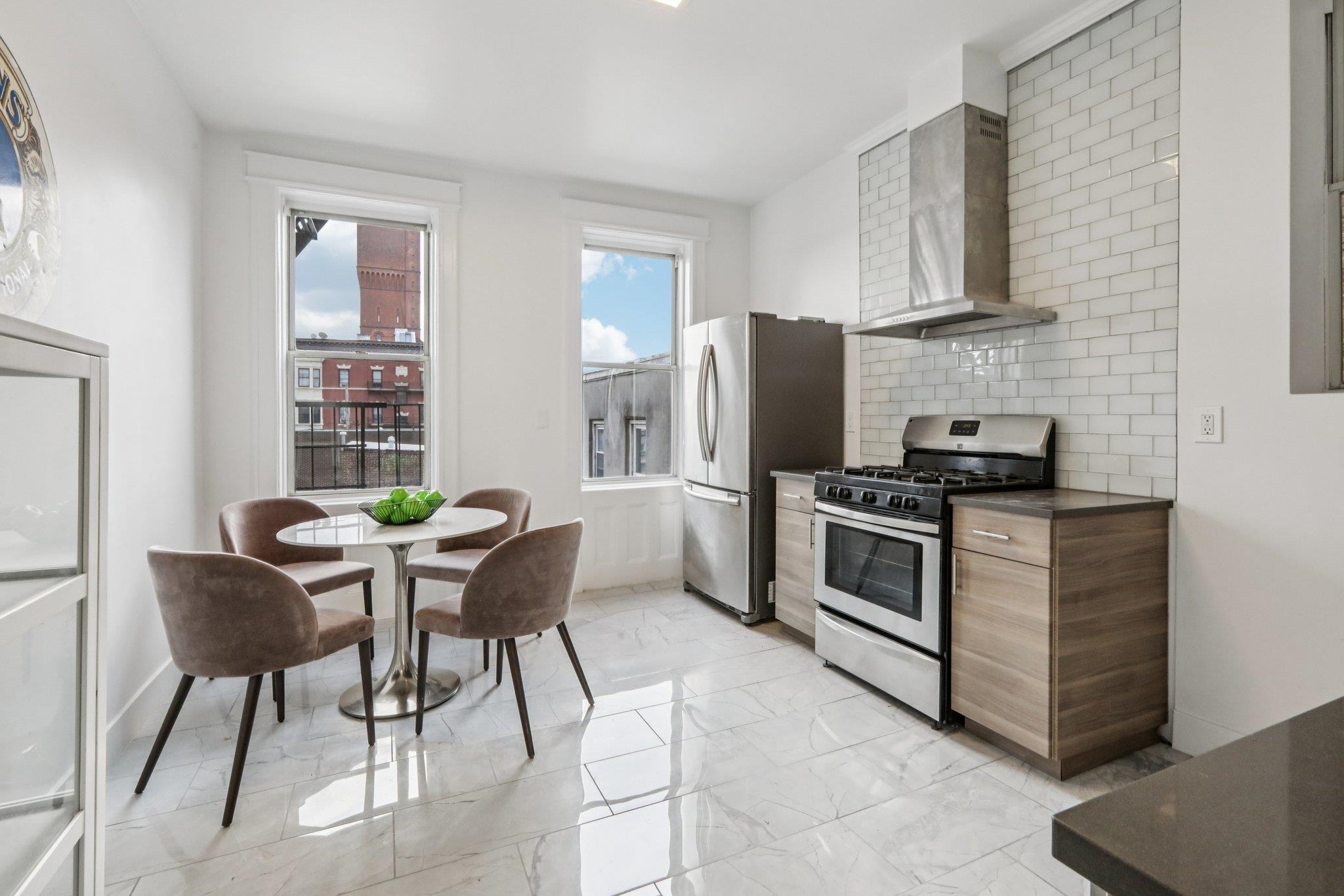 97 Clifton Terrace, Unit 6 Weehawken, NJ 07086 - Photo 10 of 36 a kitchen with stainless steel appliances kitchen island a table chairs in it and a window