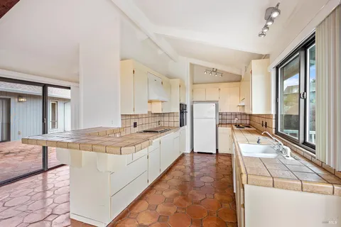 a large kitchen with kitchen island a large counter top and stainless steel appliances