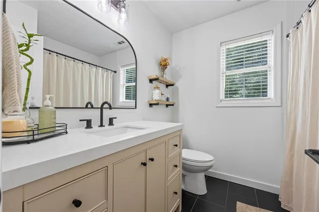 a bathroom with a granite countertop sink a toilet and a mirror