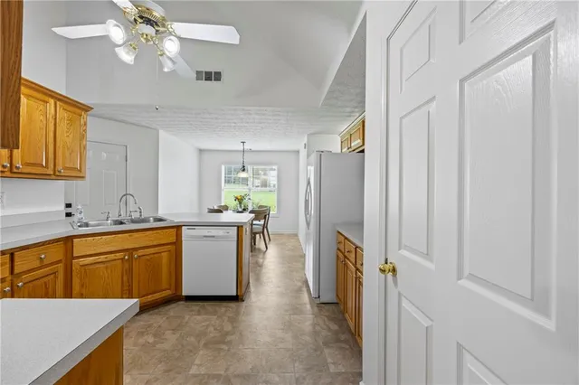 a kitchen with a refrigerator a sink dishwasher a stove and a dining table with wooden floor