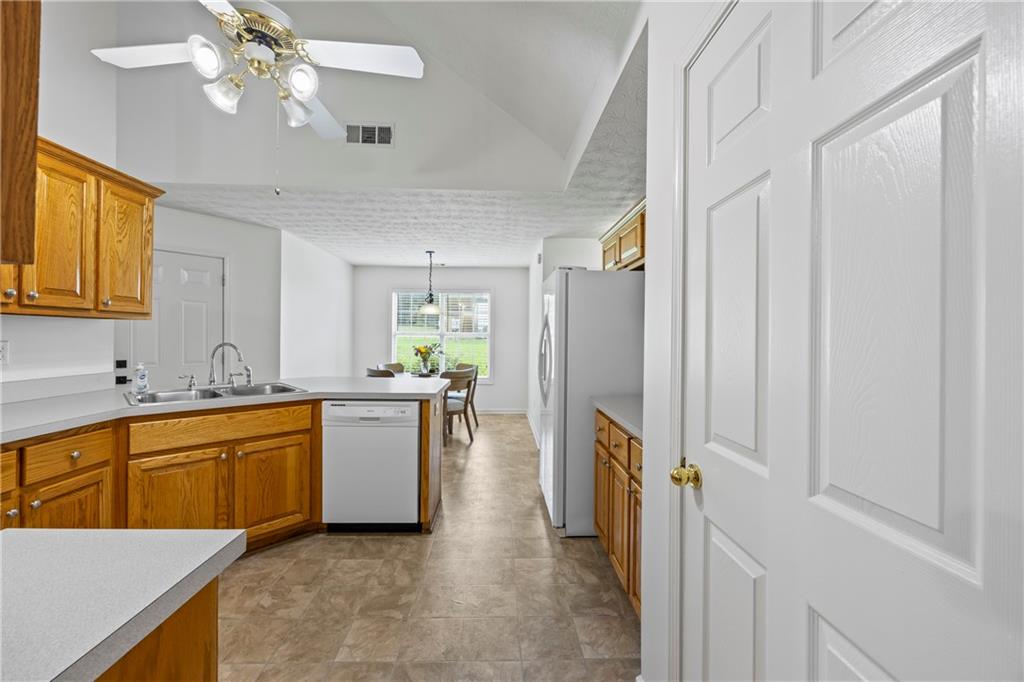 2630 Track Way Dacula, GA 30019 - Photo 4 of 27 a kitchen with a refrigerator a sink dishwasher a stove and a dining table with wooden floor