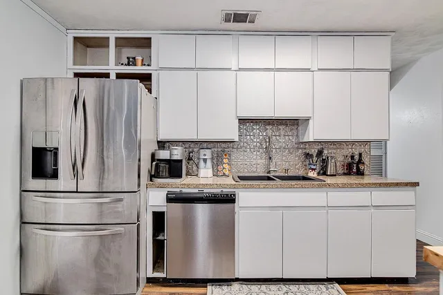 a kitchen with stainless steel appliances granite countertop a refrigerator sink and white cabinets