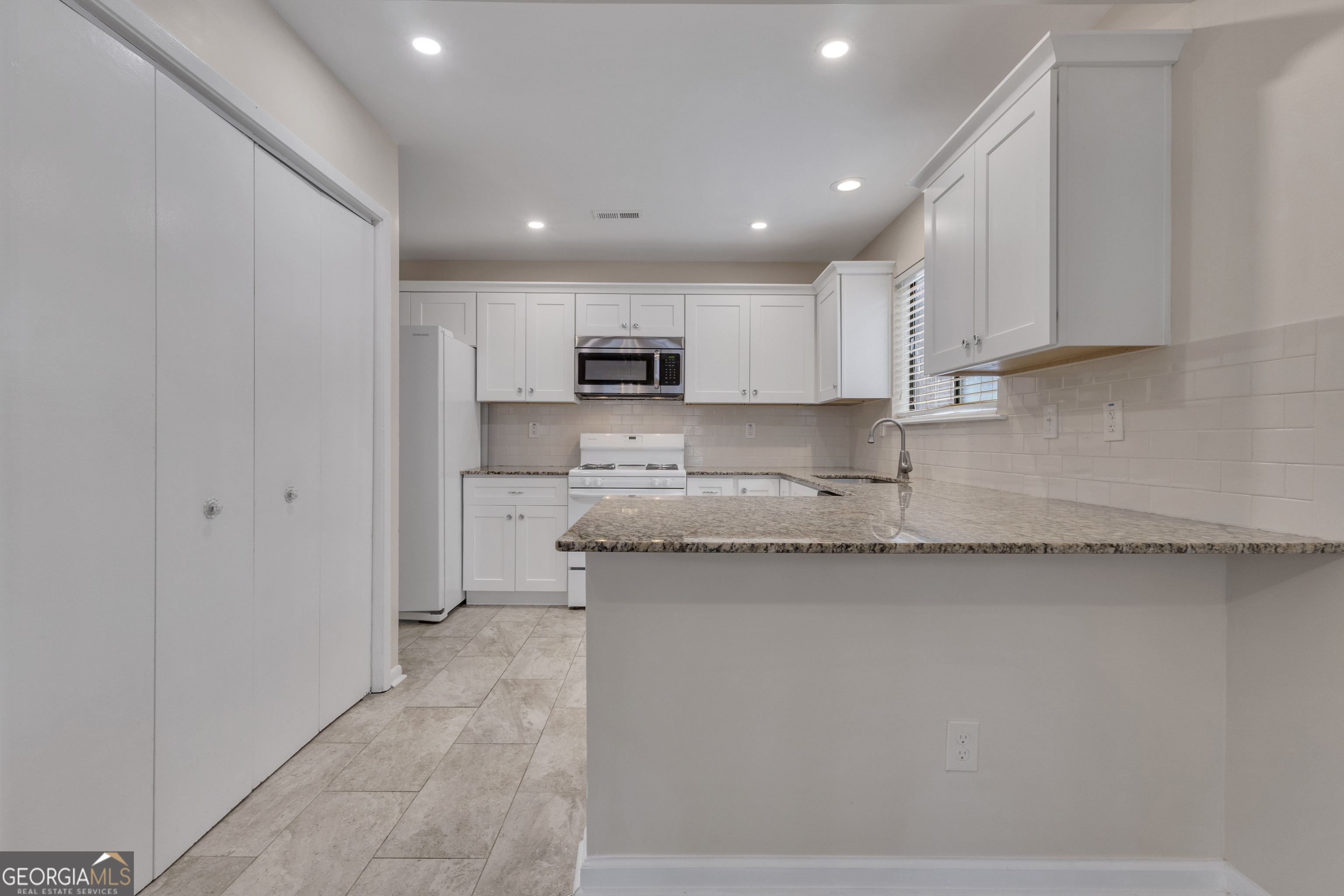 101 Dove Rise Peachtree City, GA 30269 - Photo 10 of 41 a large kitchen with stainless steel appliances granite countertop a sink a stove a refrigerator and white cabinets