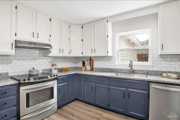 a kitchen with granite countertop cabinets stainless steel appliances a sink and dishwasher with wooden floor