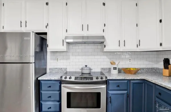a kitchen with stainless steel appliances granite countertop a stove a refrigerator and a white cabinets