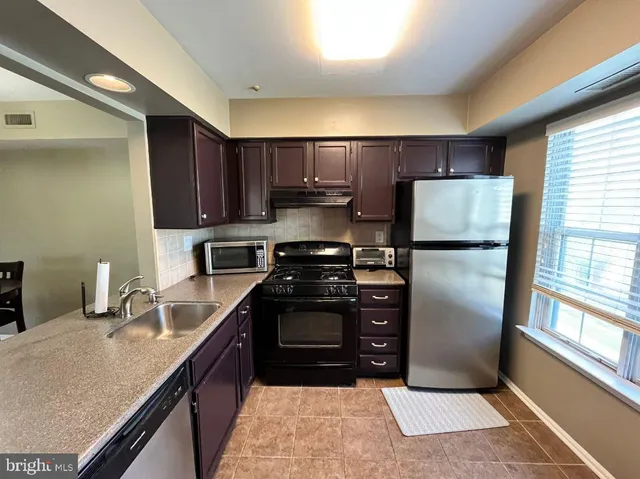 a kitchen with stainless steel appliances granite countertop a refrigerator stove and sink