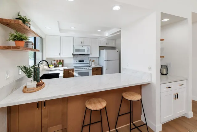 a kitchen with white cabinets and chairs