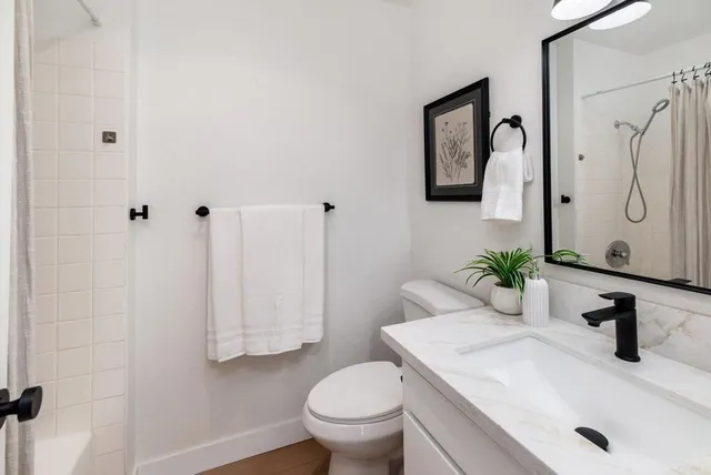 a bathroom with a granite countertop sink toilet and a mirror