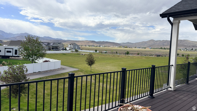 7889 Bristlecone Road Eagle Mountain, UT 84005 - Photo 36 of 42 Expansive outdoor deck featuring dark composite decking and black metal railings, overlooking a large green lawn area with distant mountains