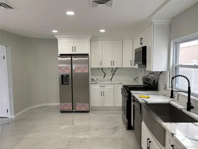 a kitchen with stainless steel appliances kitchen island granite countertop a sink and a refrigerator