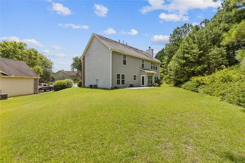 a view of a brick house with plants and large tree