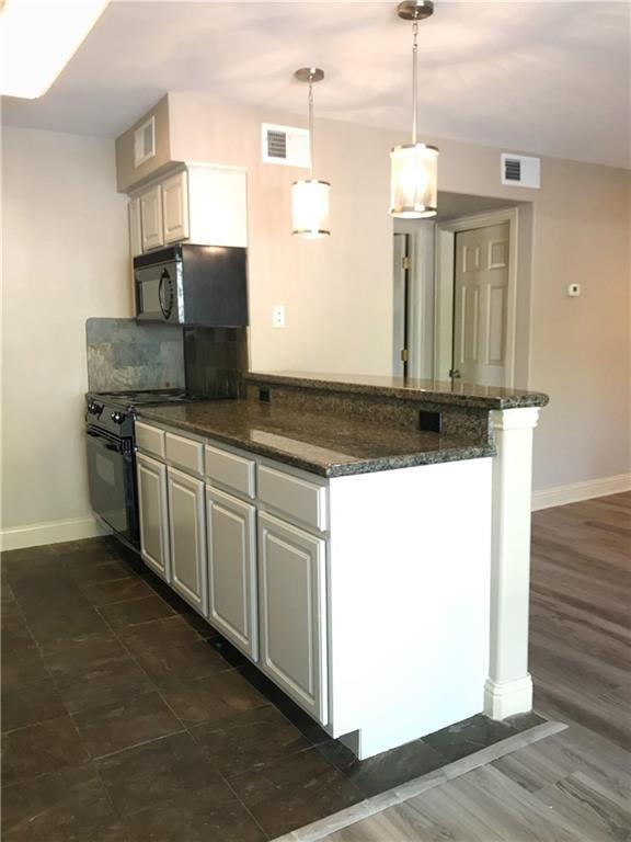 500 East Riverside Drive, Unit 154 Austin, TX 78704 - Photo 2 of 14 Kitchen featuring white cabinetry, dark stone countertops, stainless steel appliances, and pendant lighting