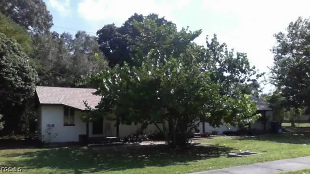 a front view of a house with a garden and tree
