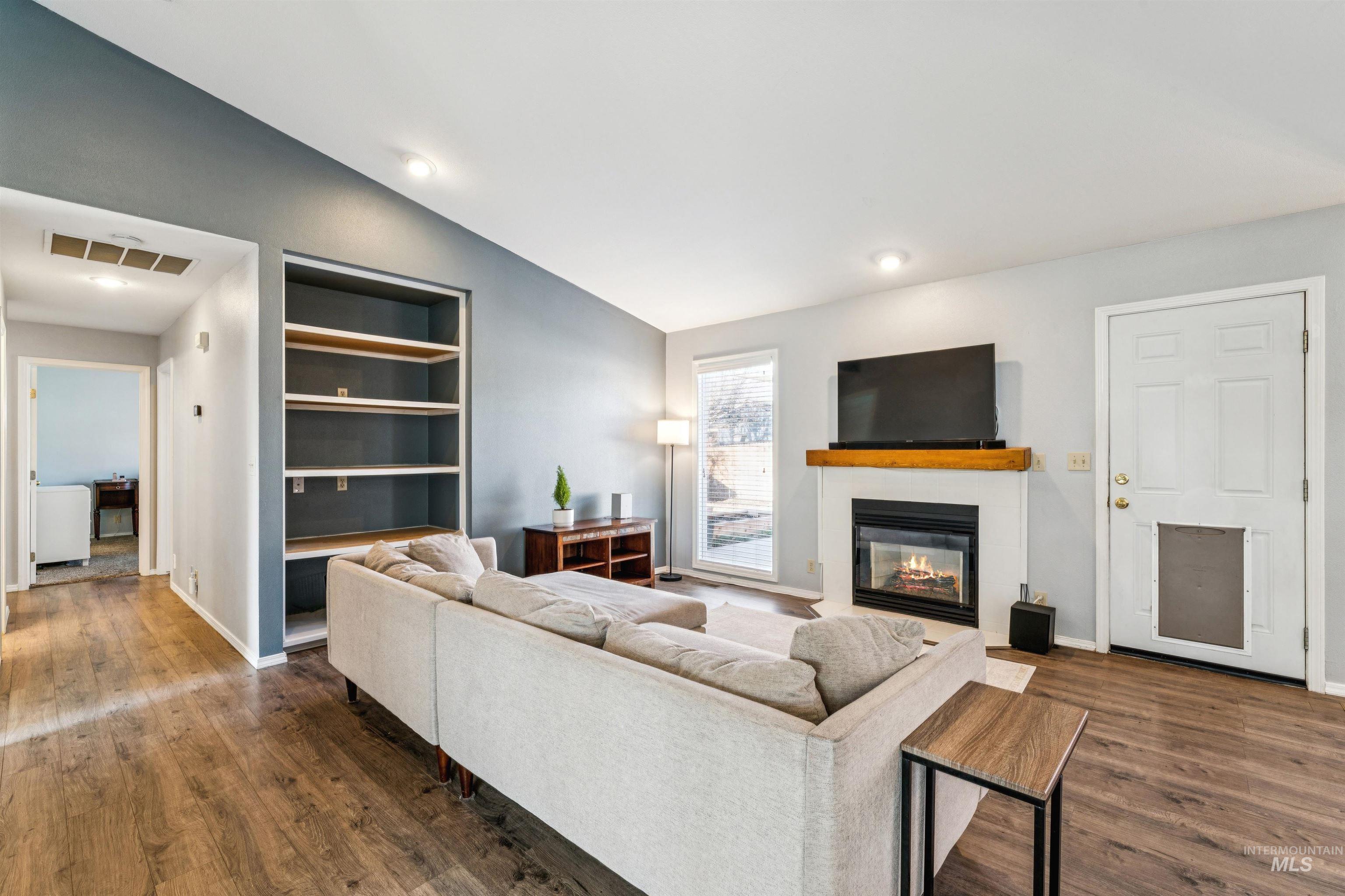 11968 West Bronte Street Boise, ID 83709 - Photo 11 of 48 Living area with vaulted ceiling, a glass covered fireplace, dark wood-type flooring, built in features, and recessed lighting
