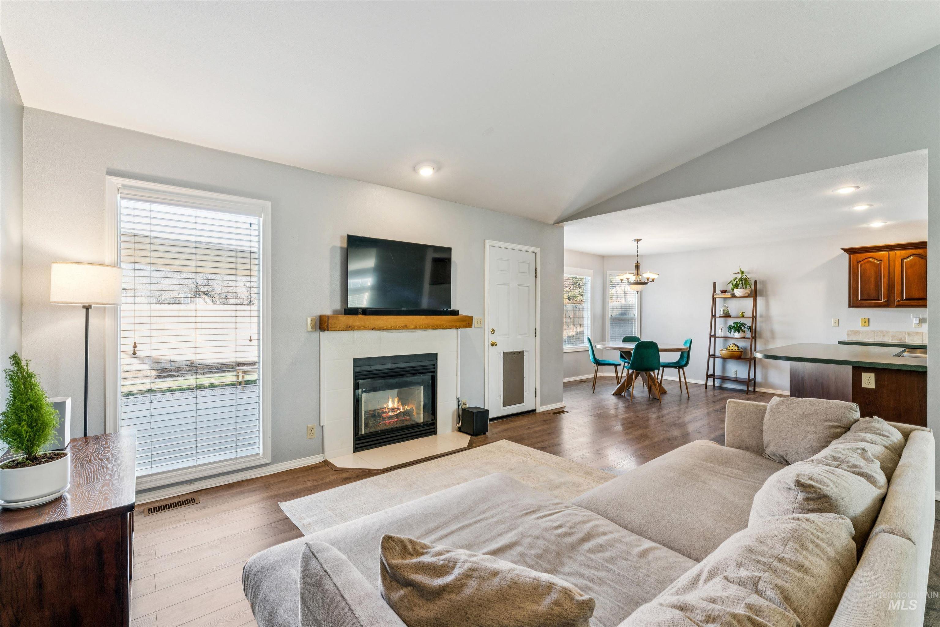 11968 West Bronte Street Boise, ID 83709 - Photo 13 of 48 Living room with lofted ceiling, recessed lighting, a glass covered fireplace, light wood-type flooring, and a chandelier