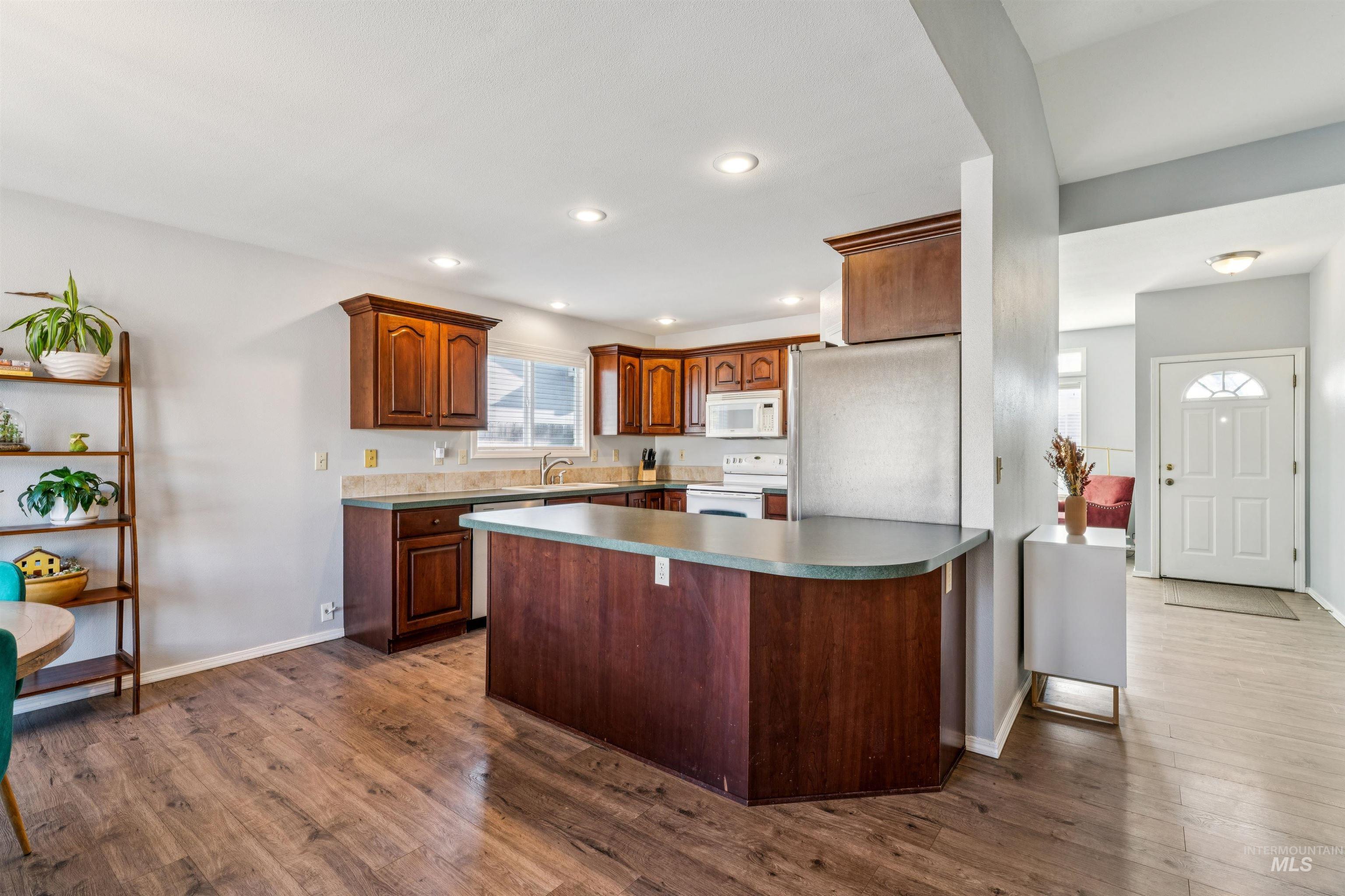 11968 West Bronte Street Boise, ID 83709 - Photo 15 of 48 Kitchen with appliances with stainless steel finishes, a kitchen bar, a peninsula, dark wood-style floors, and recessed lighting