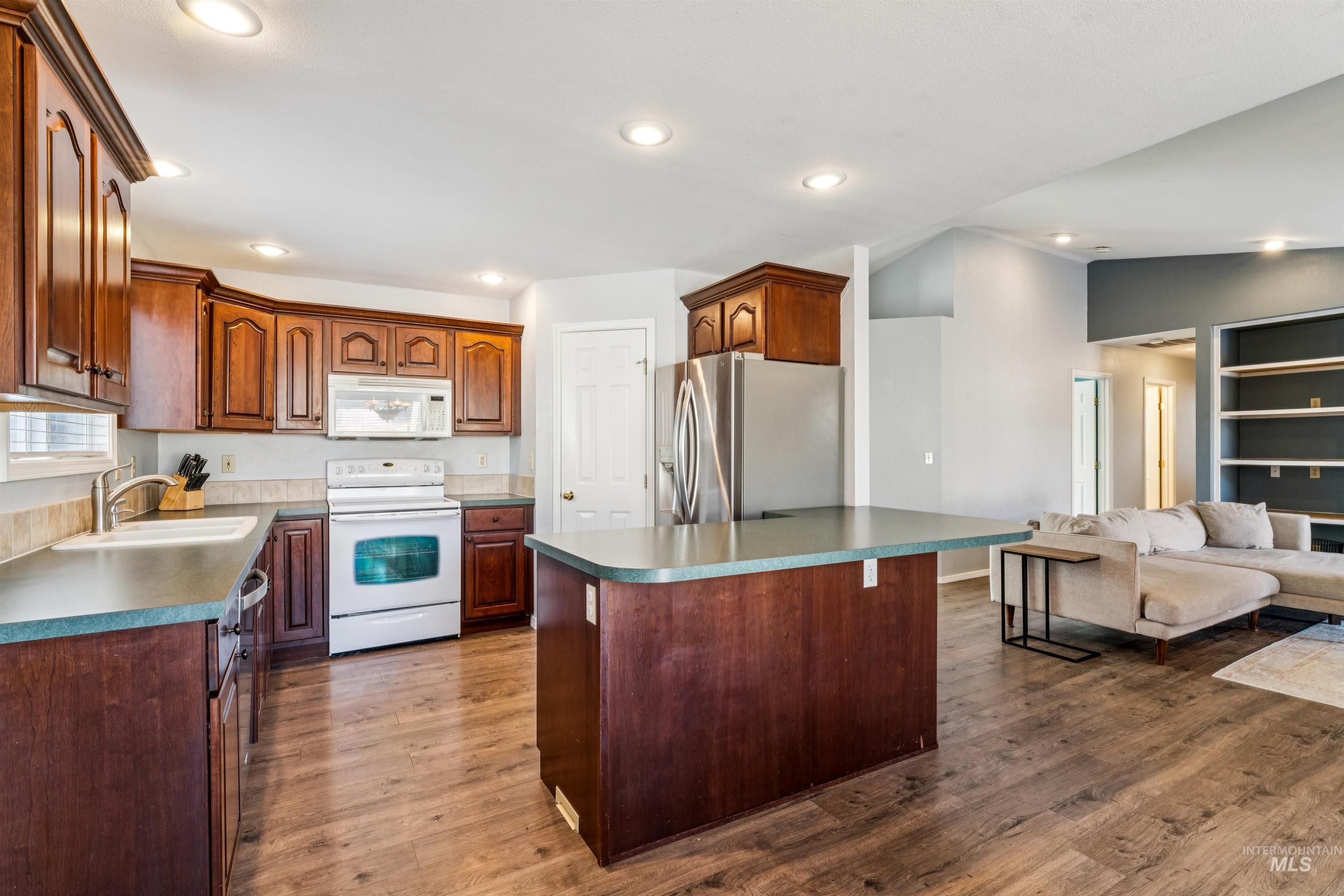 11968 West Bronte Street Boise, ID 83709 - Photo 47 of 48 Kitchen with white appliances, open floor plan, dark countertops, light wood-type flooring, and vaulted ceiling