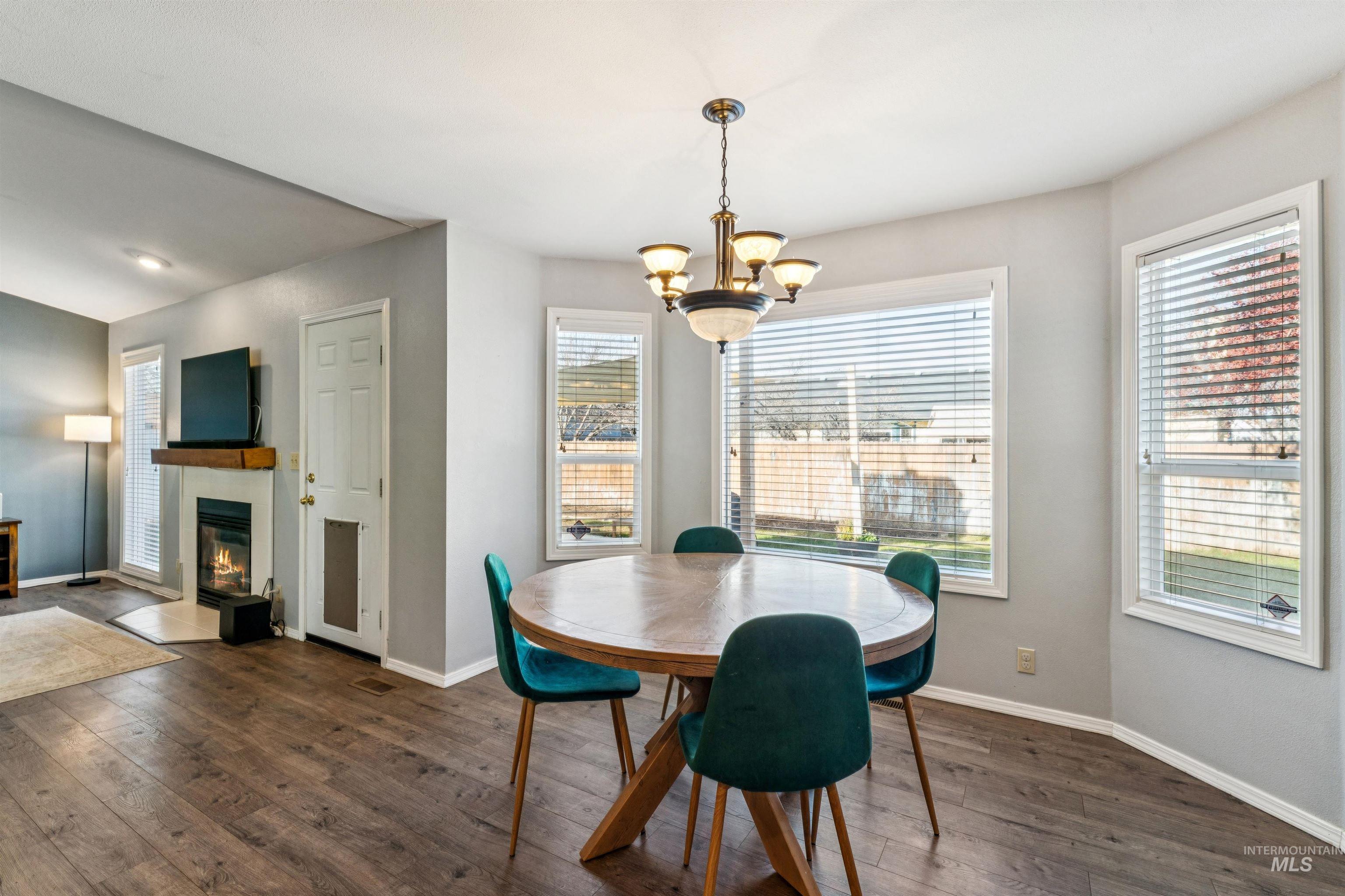 11968 West Bronte Street Boise, ID 83709 - Photo 20 of 48 Dining area featuring a glass covered fireplace, dark wood-type flooring, and a chandelier