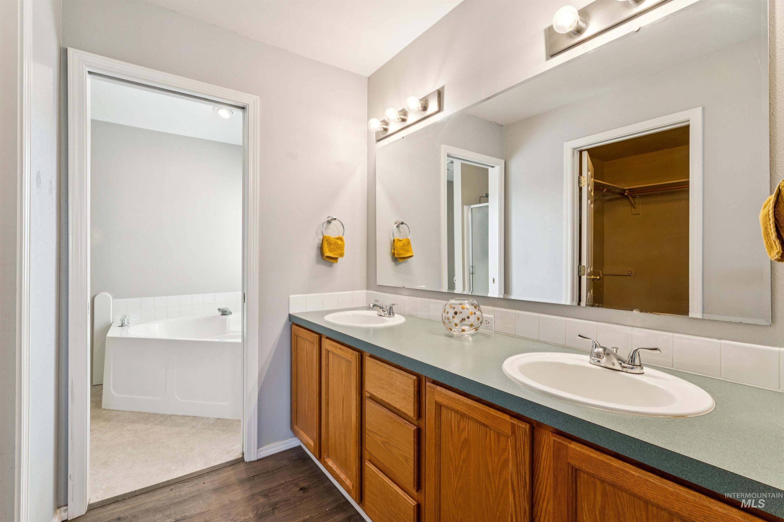 11968 West Bronte Street Boise, ID 83709 - Photo 24 of 48 Bathroom featuring double vanity, a spacious closet, dark wood finished floors, a garden tub, and a shower with shower door