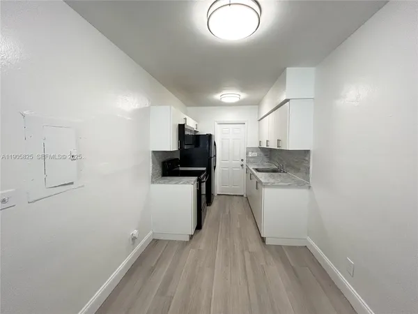 a kitchen with a refrigerator and white cabinets