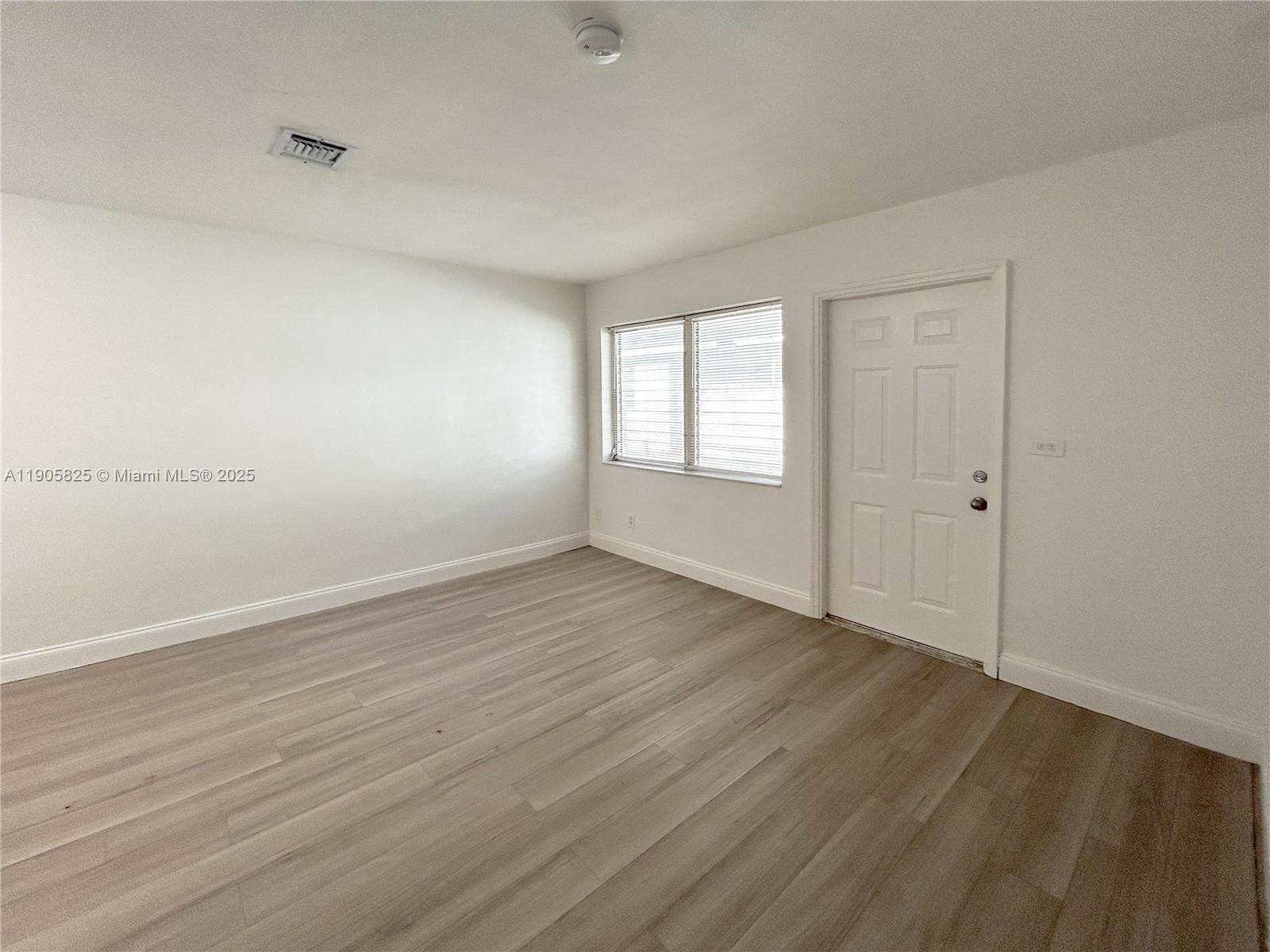 738 Northeast 86th Street, Unit 6 Miami, FL 33138 - Photo 5 of 10 an empty room with wooden floor and windows