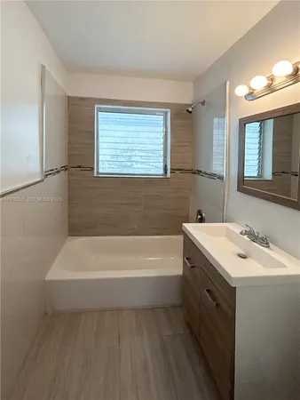 a bathroom with a bathtub a sink a window and a shower
