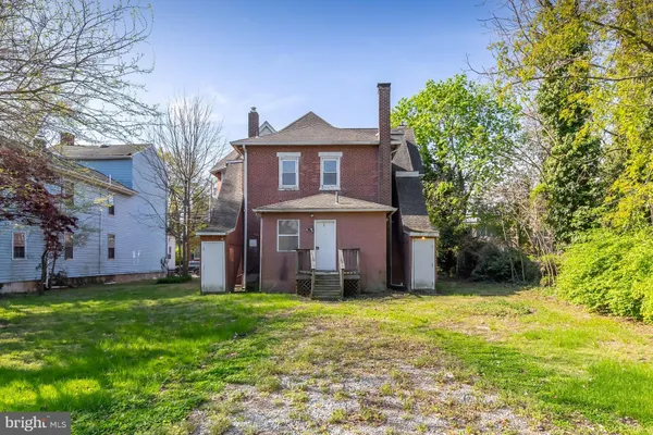 a view of a brick house with a big yard and large trees